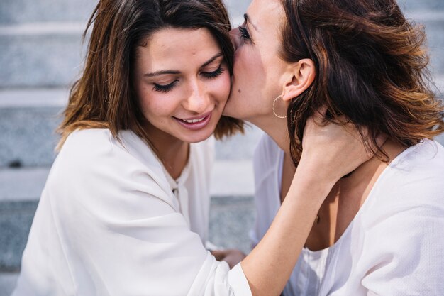 Mutter, die daughther in der Backe küsst