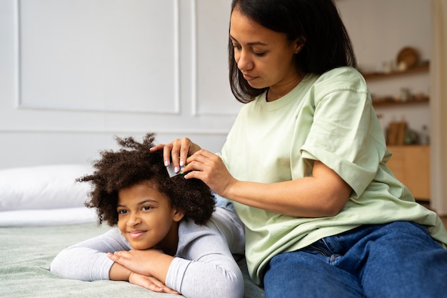 Mutter, die die Haare des Mädchens kämmt, Seitenansicht