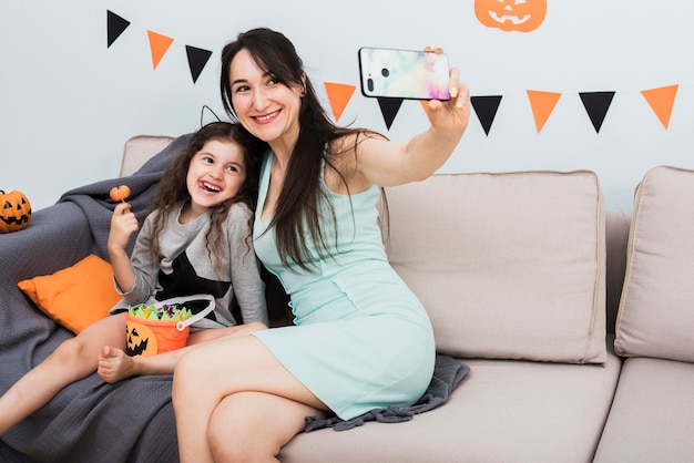 Mutter, die ein selfie mit Tochter an Halloween nimmt