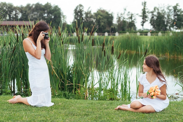 Kostenloses Foto mutter, die foto der tochter durch den see macht