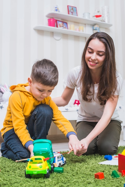 Mutter, die Spielzeugauto mit Jungen spielt