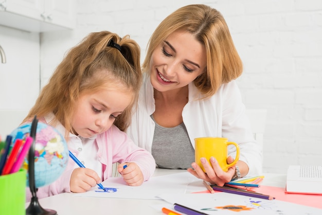 Mutter, die Tochter bei ihren Hausaufgaben hilft