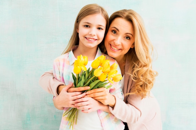 Mutter, die Tochter umfasst und Tulpen hält