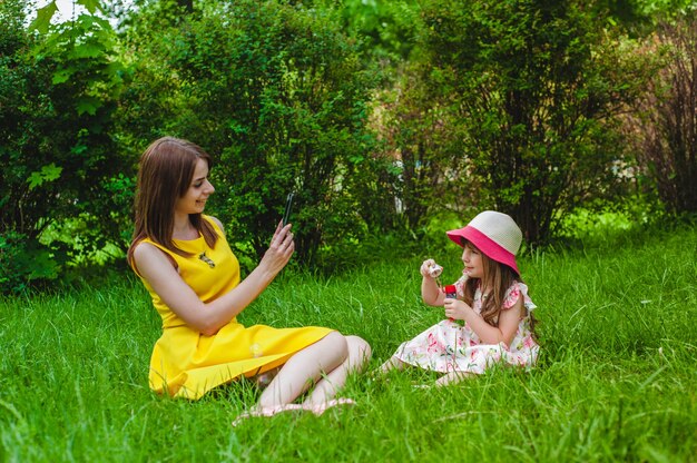 Mutter fotografiert ihre Tochter während bläst Seifenblasen