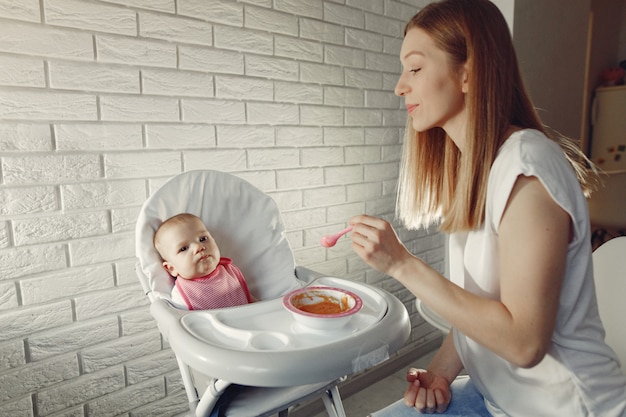 Mutter füttert ihr kleines Baby in einer Küche