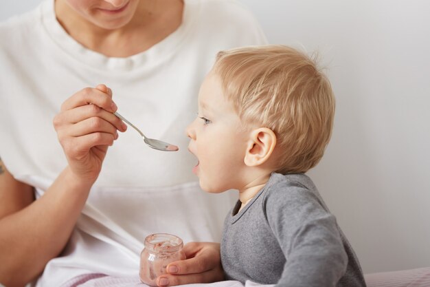 Mutter füttert ihren kleinen Jungen mit Löffel