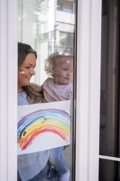 Mutter hält Kind und schaut durch das Fenster