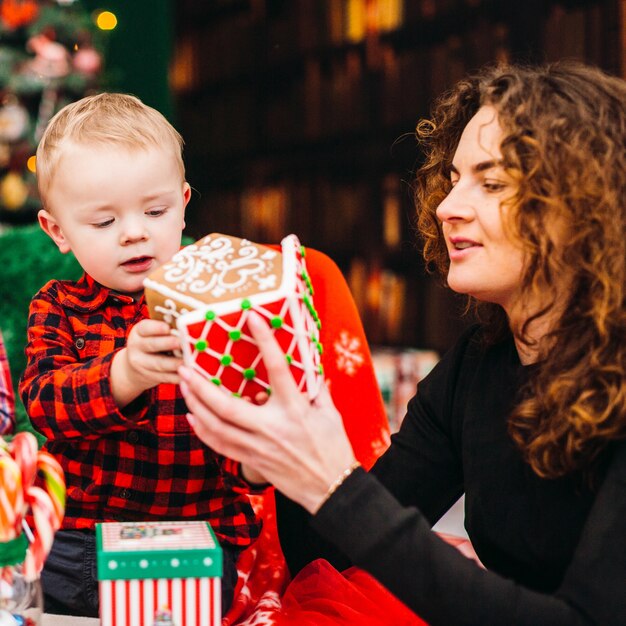 Mutter hat Spaß mit ihrem Sohn, der im Raum sitzt, der für Weihnachten und neues Jahr gekleidet wird