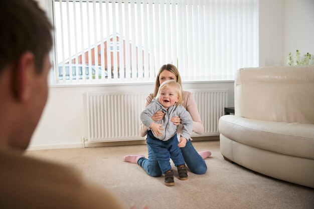 Mutter hilft Kind beim Gehen zu Hause