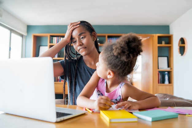 Mutter hilft und unterstützt ihre Tochter bei der Online-Schule, während sie zu Hause bleibt. Neues normales Lifestyle-Konzept. Monoparentales Konzept.