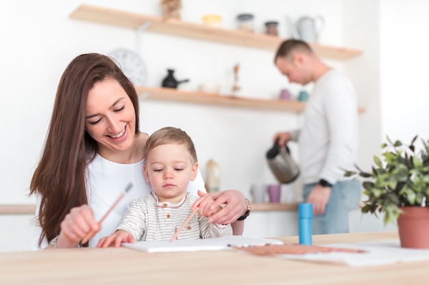 Mutter in der Küche mit Kind und defokussiertem Vater