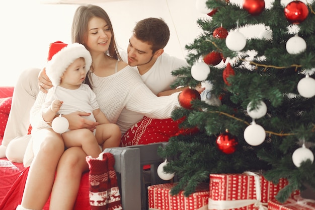 Mutter in einem weißen Pullover. Familie mit Weihnachtsgeschenken. Kind mit den Eltern in einer Weihnachtsdekoration.