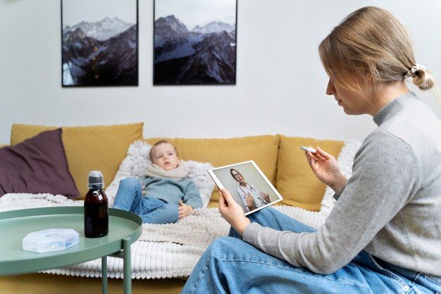 Mutter kümmert sich um ihr Kind und telekonsultiert mit dem Arzt