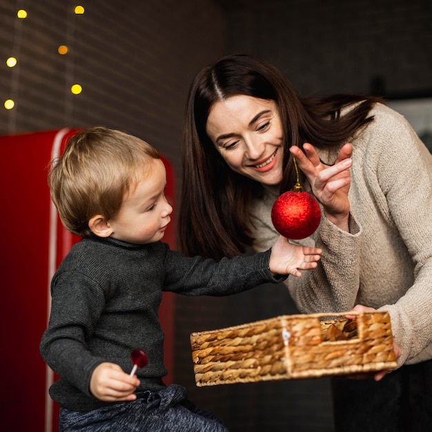 Mutter lehrt Sohn, wie man Weihnachtsbaum schmückt