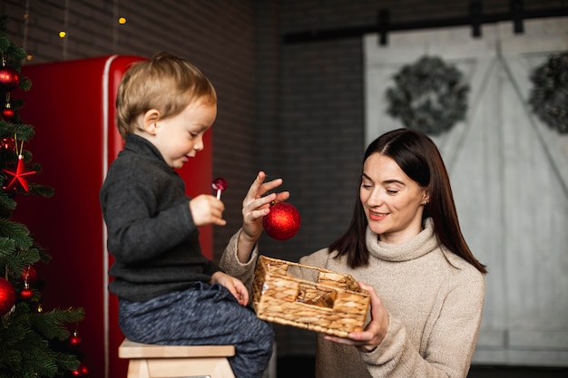 Mutter lehrt Sohn, wie man Weihnachtsbaum schmückt