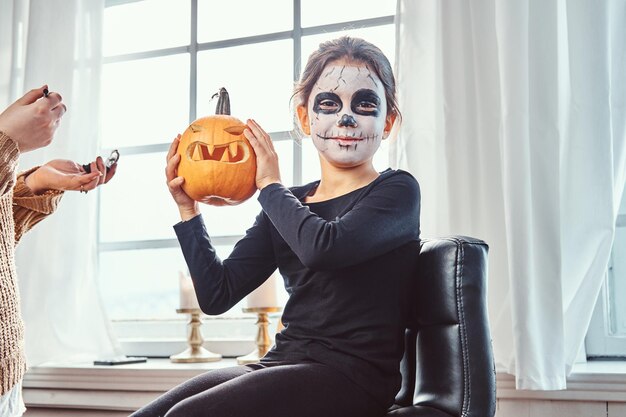 Mutter malt Tochter Gesicht für Halloween-Party.