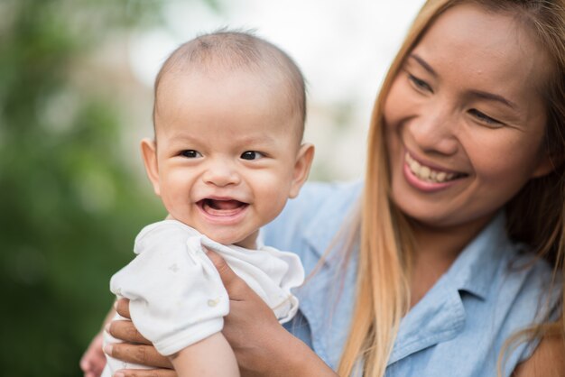 Mutter mit Baby, lachend und im Park spielend