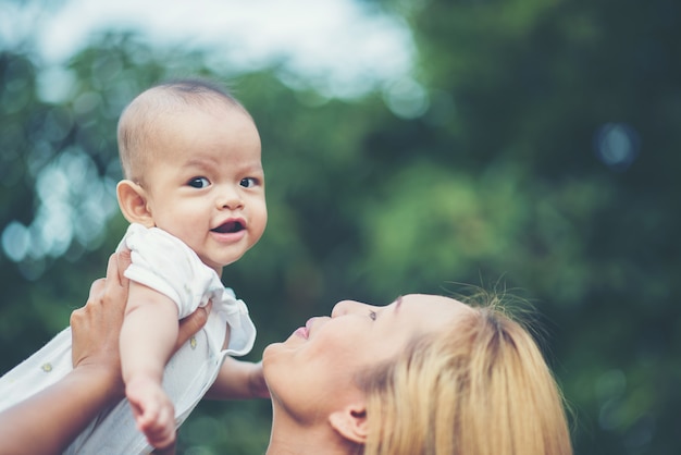 Mutter mit Baby, lachend und im Park spielend