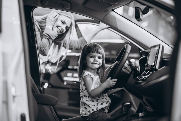 Mutter mit dem kleinen Daughet, der in einem Auto in einem Autosalon sitzt