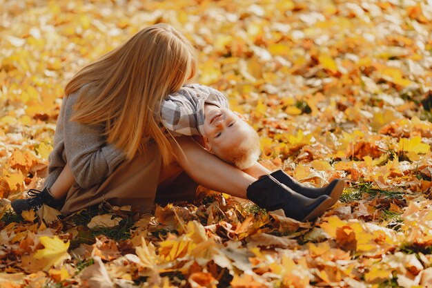 Mutter mit dem kleinen Sohn, der auf einem Herbstgebiet sitzt