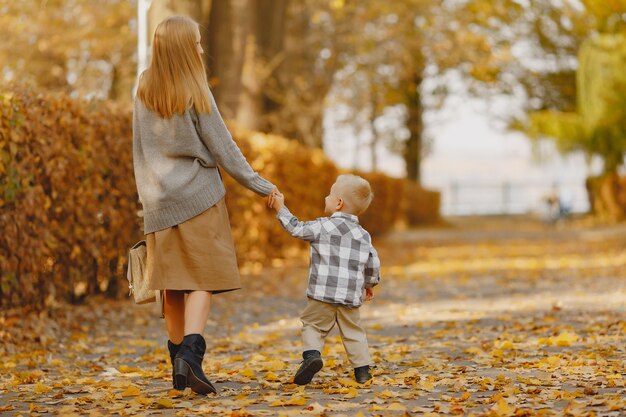 Mutter mit dem kleinen Sohn, der auf einem Herbstgebiet spielt