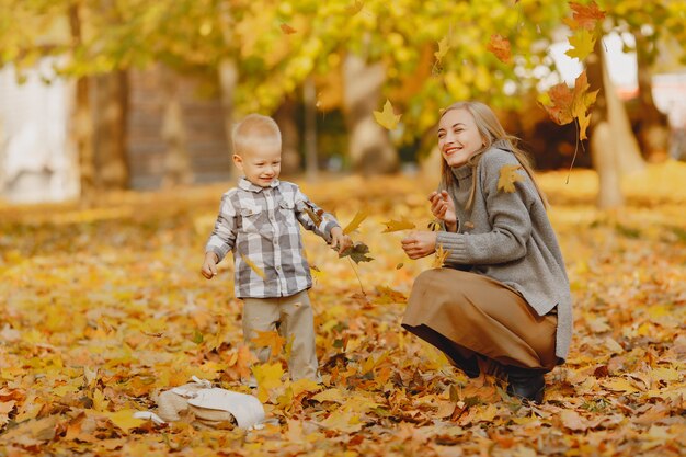 Mutter mit dem kleinen Sohn, der auf einem Herbstgebiet spielt