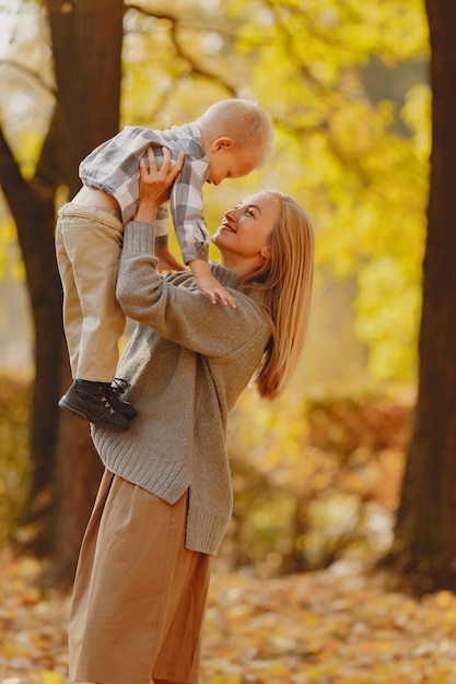 Mutter mit dem kleinen Sohn, der auf einem Herbstgebiet spielt