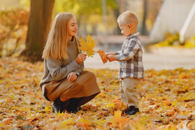 Mutter mit dem kleinen Sohn, der auf einem Herbstgebiet spielt