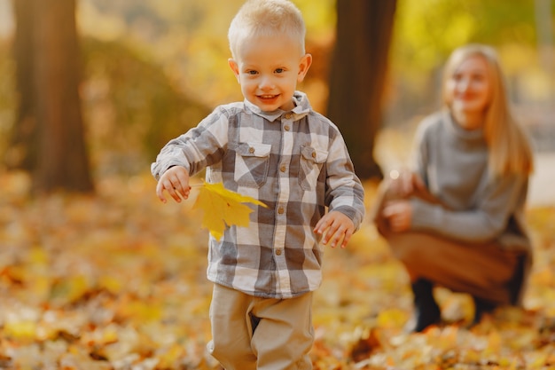 Mutter mit dem kleinen Sohn, der auf einem Herbstgebiet spielt