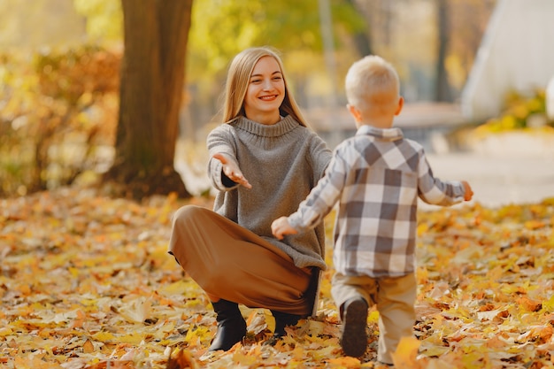 Mutter mit dem kleinen Sohn, der auf einem Herbstgebiet spielt