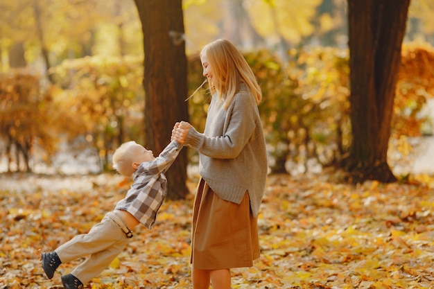 Mutter mit dem kleinen Sohn, der auf einem Herbstgebiet spielt