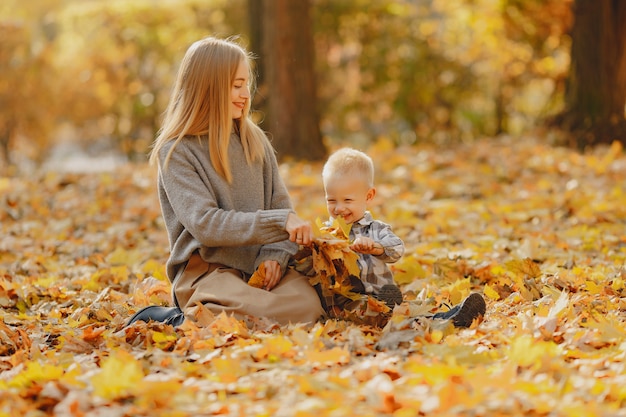 Mutter mit dem kleinen Sohn, der auf einem Herbstgebiet spielt