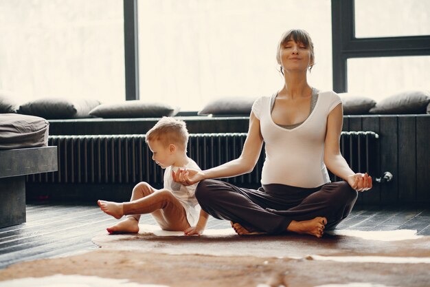 Mutter mit dem kleinen Sohn, der zu Hause Yoga tut