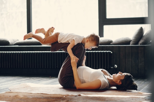 Mutter mit dem kleinen Sohn, der zu Hause Yoga tut