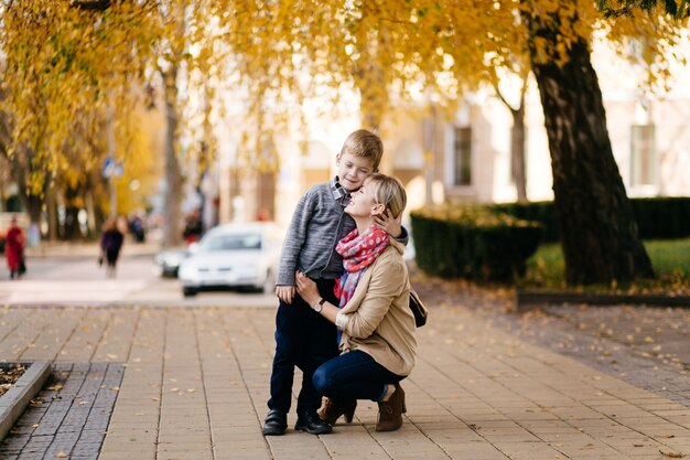 Mutter mit dem Sohn, der im Herbst im Freien geht