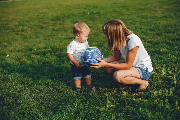 Mutter mit dem Sohn, der in einem Sommerpark spielt