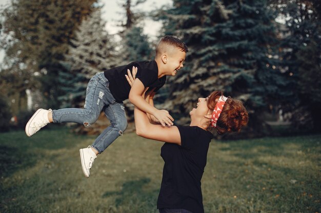 Mutter mit dem Sohn, der in einem Sommerpark spielt