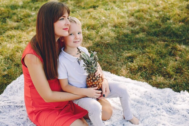 Mutter mit dem Sohn, der in einem Sommerpark spielt