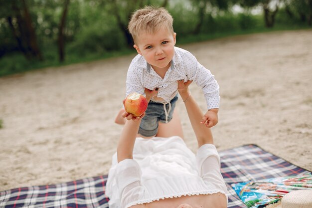 Mutter mit dem Sohn, der in einem Sommerpark spielt