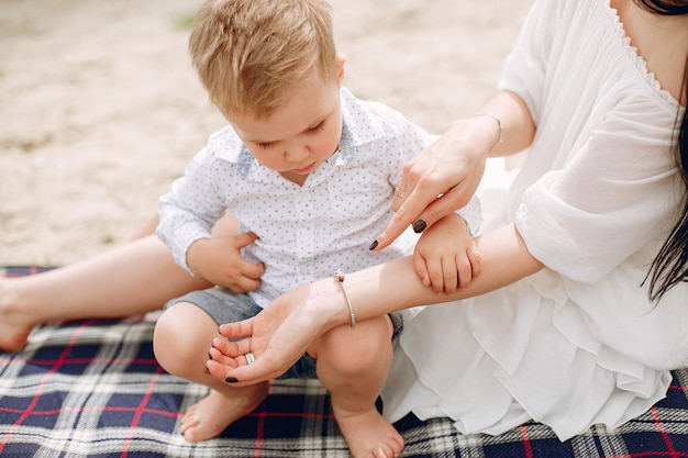 Mutter mit dem Sohn, der in einem Sommerpark spielt