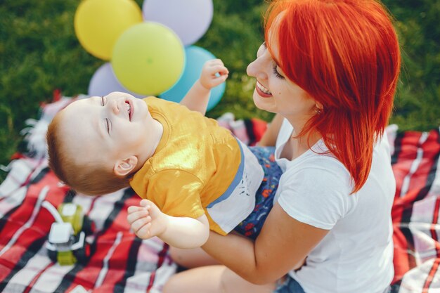 Mutter mit dem Sohn, der in einem Sommerpark spielt