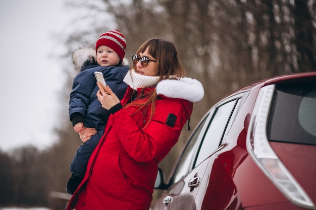 Mutter mit dem Sohn, der mit dem Auto steht