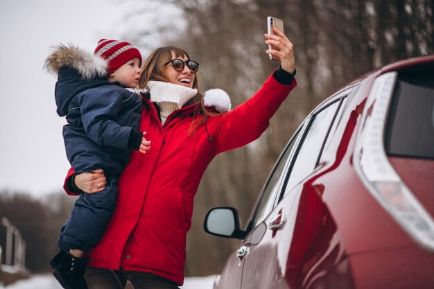 Mutter mit dem Sohn, der mit dem Auto steht