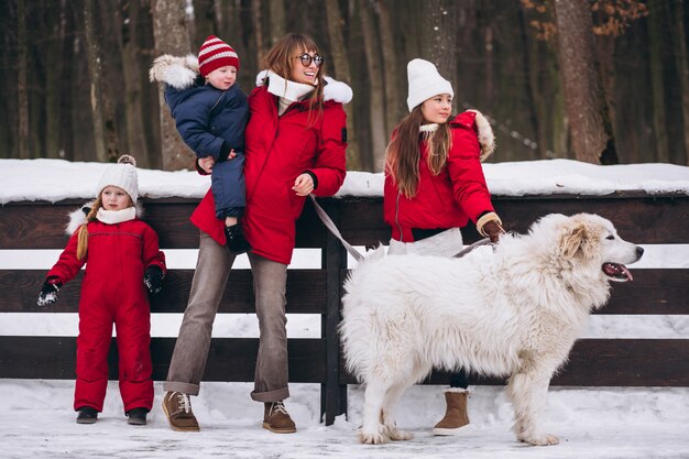 Mutter mit den Kindern und Hund, die draußen im Winter spielen