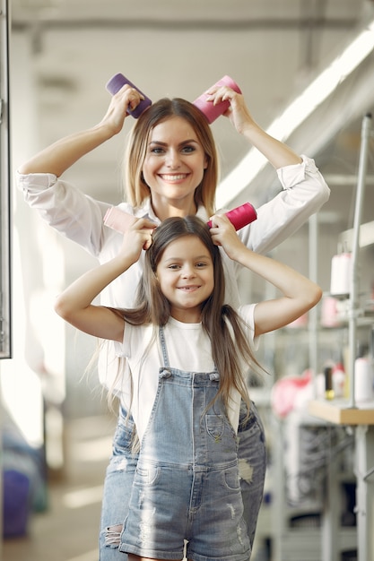 Mutter mit der kleinen Tochter, die am Gewebe mit Thread steht