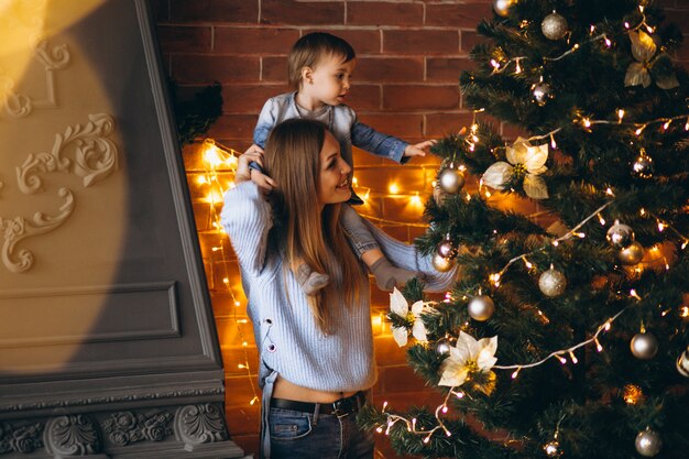 Mutter mit der kleinen Tochter, die Weihnachtsbaum verziert