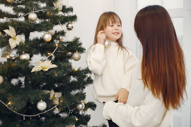 Mutter mit der netten Tochter, die nahen Weihnachtsbaum steht