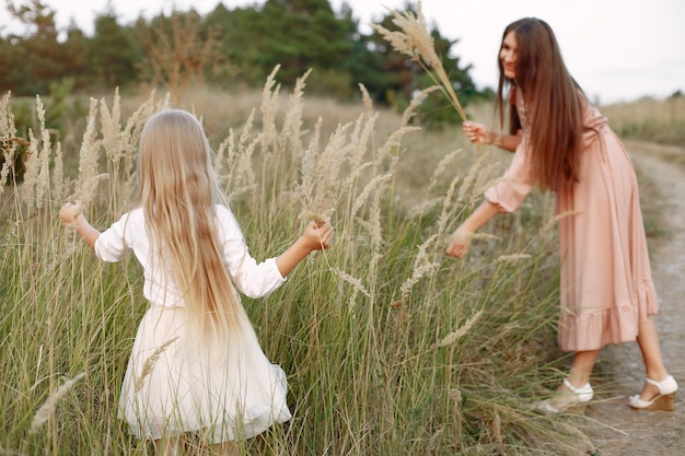 Mutter mit der Tochter, die auf einem Herbstgebiet spielt