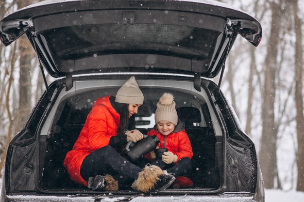 Mutter mit der Tochter, die im Auto im Winter sitzt