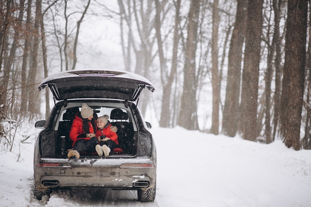 Mutter mit der Tochter, die im Auto im Winter sitzt